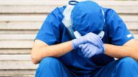 Overworked health care worker sitting and looking down