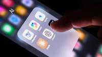 Various artificial intelligence icons on a smart phone with a finger about to click on one.