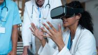 Doctors wearing face masks sitting at a table and using VR glasses.